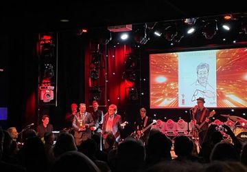 Scene med prisvinner. Publikum i forgrunn.  