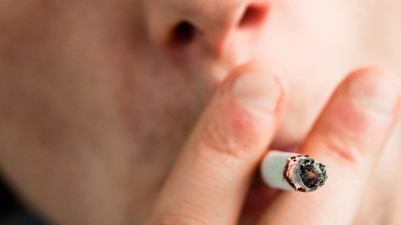 Nærbilde av person med sigarett i munnen