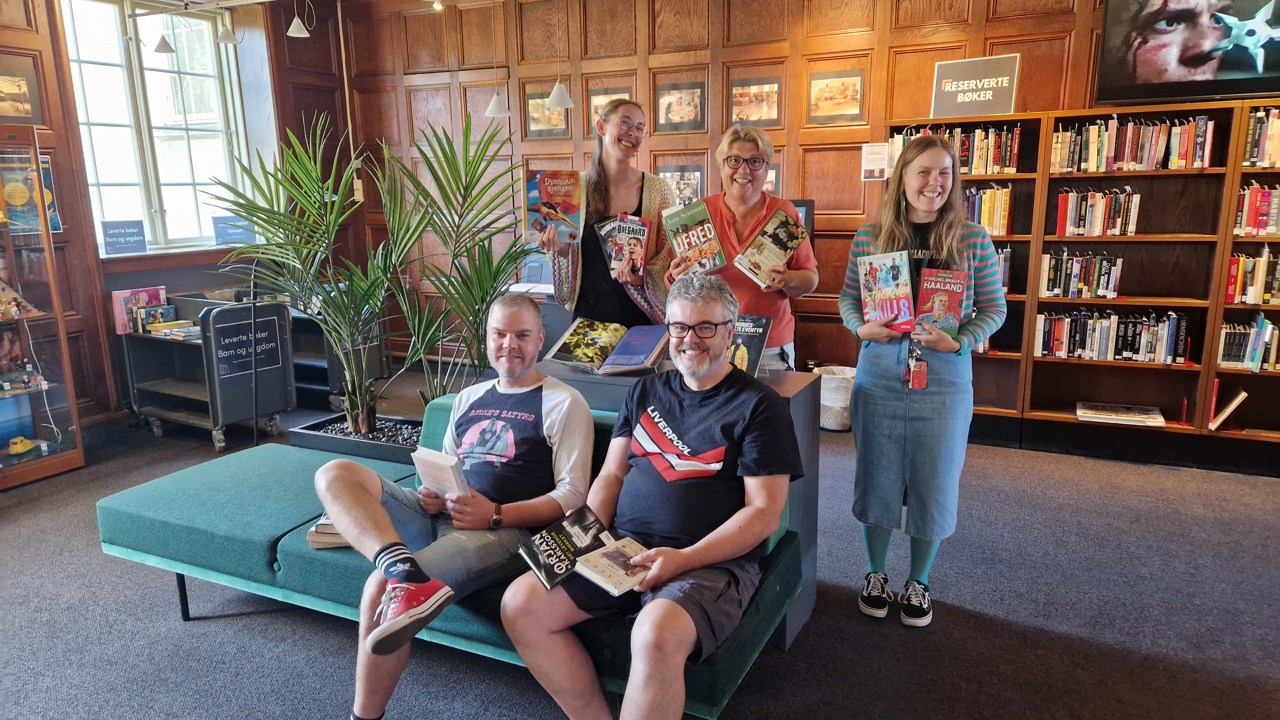 Ansatte ved Fredrikstad bibliotek markerer den beste utlånsmåneden i bibliotekets historie. Bak fra venstre: Andrea Wold Johansen, Anne Trine Skjulhaug og Ann-Charlott Klausen Christensen. Foran fra venstre: Stig Kaino og Dag Einar Steinnes. Foto: Fredrikstad bibliotek.