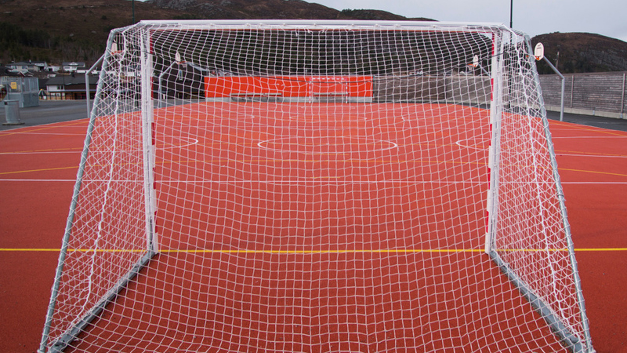 Fotballbane med rød matte og fotballmål,