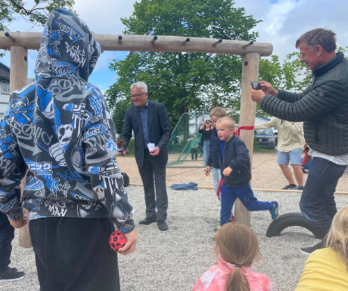 Voksne og barn samlet på en lekeplass.