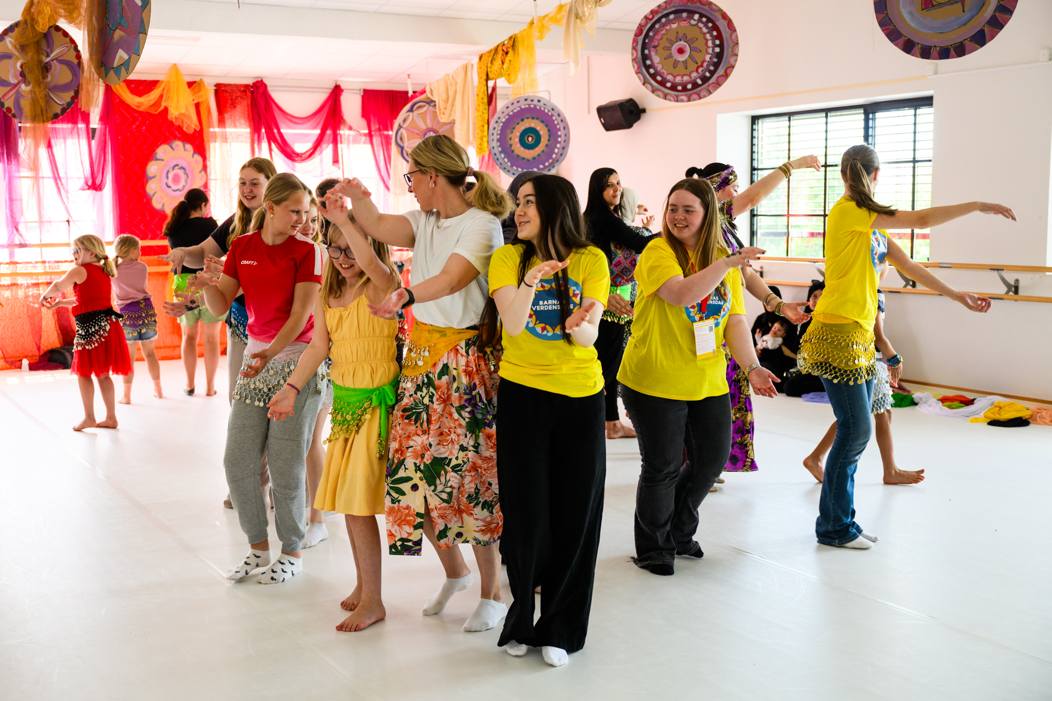 Mange glade ungdommer og barn danser i et dansestudio 