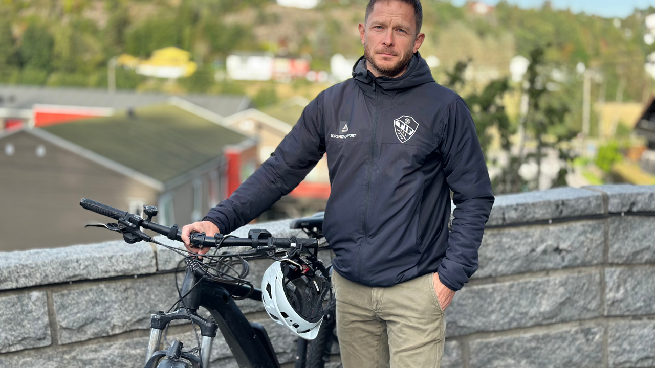 Mann står og holder i en elsykkel 